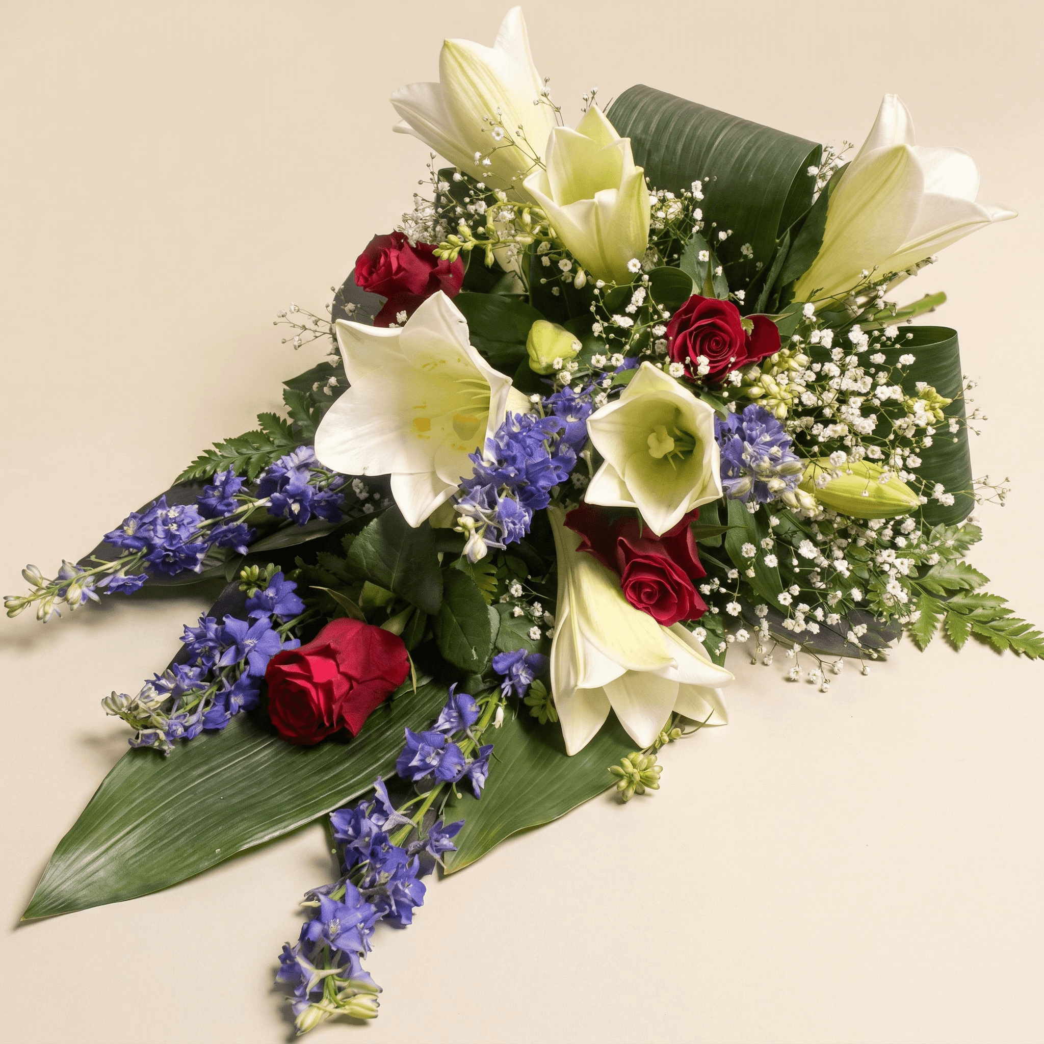 Liggande sorgarrangemang med liljor och riddarsporrar